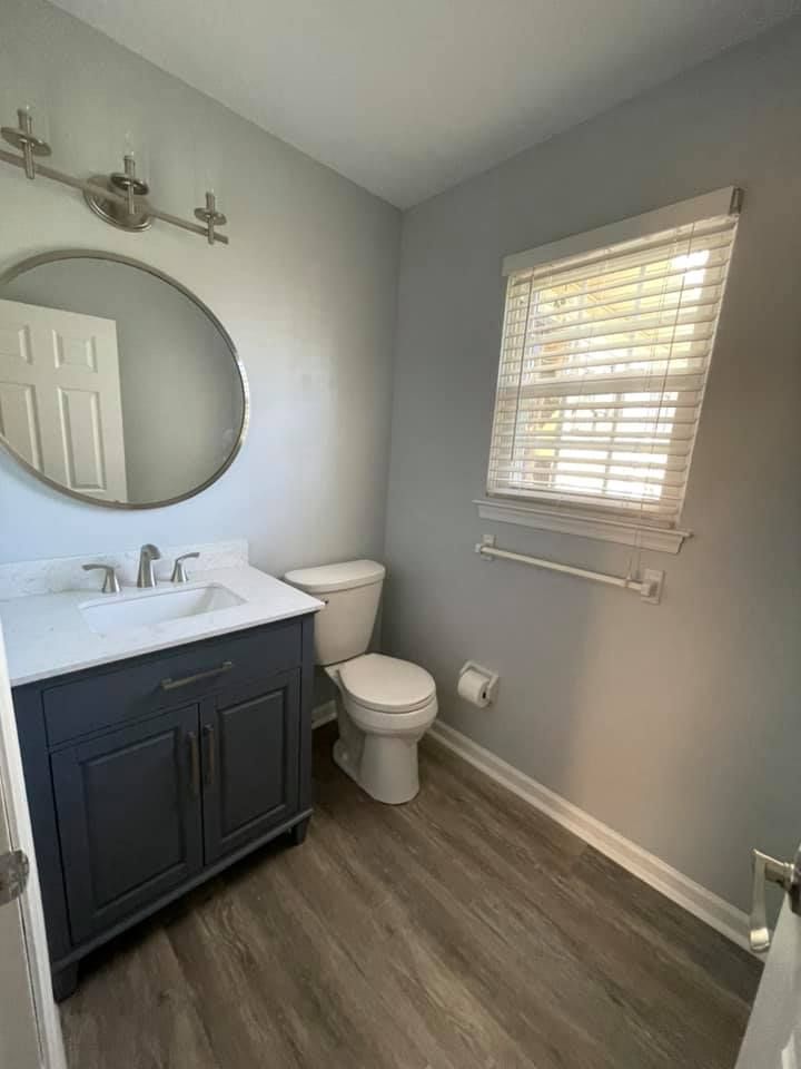 A bathroom with a sink , toilet , mirror and window.