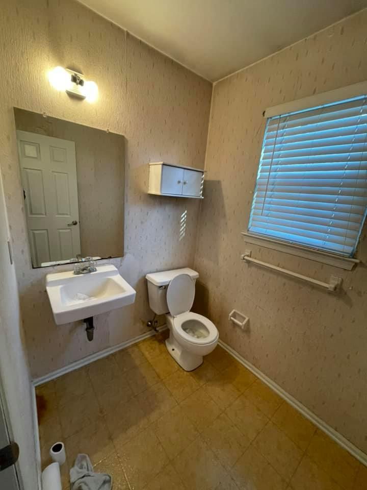 A bathroom with a toilet , sink and mirror.