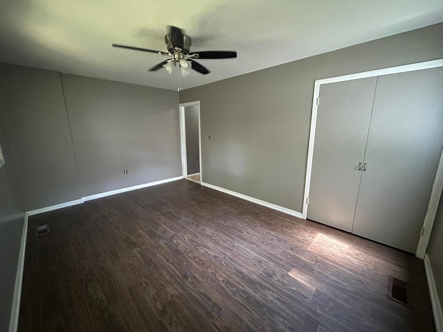 An empty room with hardwood floors and a ceiling fan.