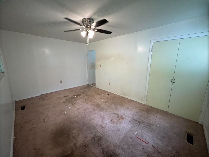 An empty bedroom with a ceiling fan and a light.