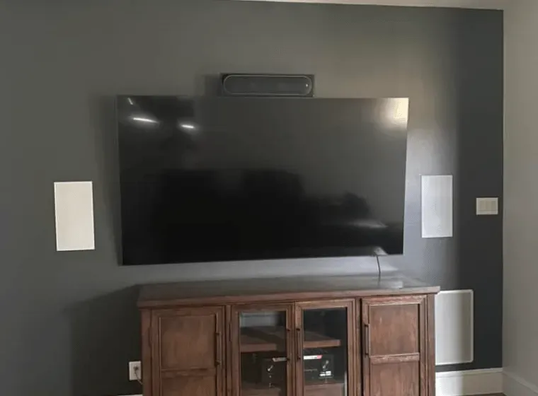 A large flat screen tv is mounted on a wall above a wooden entertainment center.
