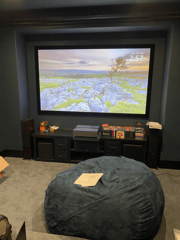 A home theater with a bean bag chair and a large screen.