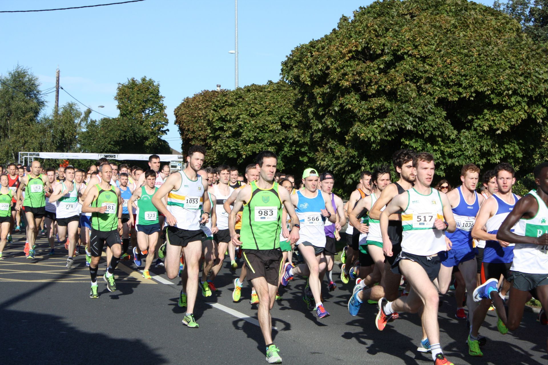A large group of runners are running down a street.