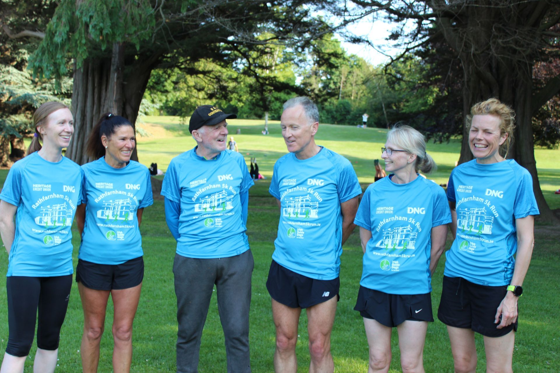 A group of people wearing blue shirts are standing in a park