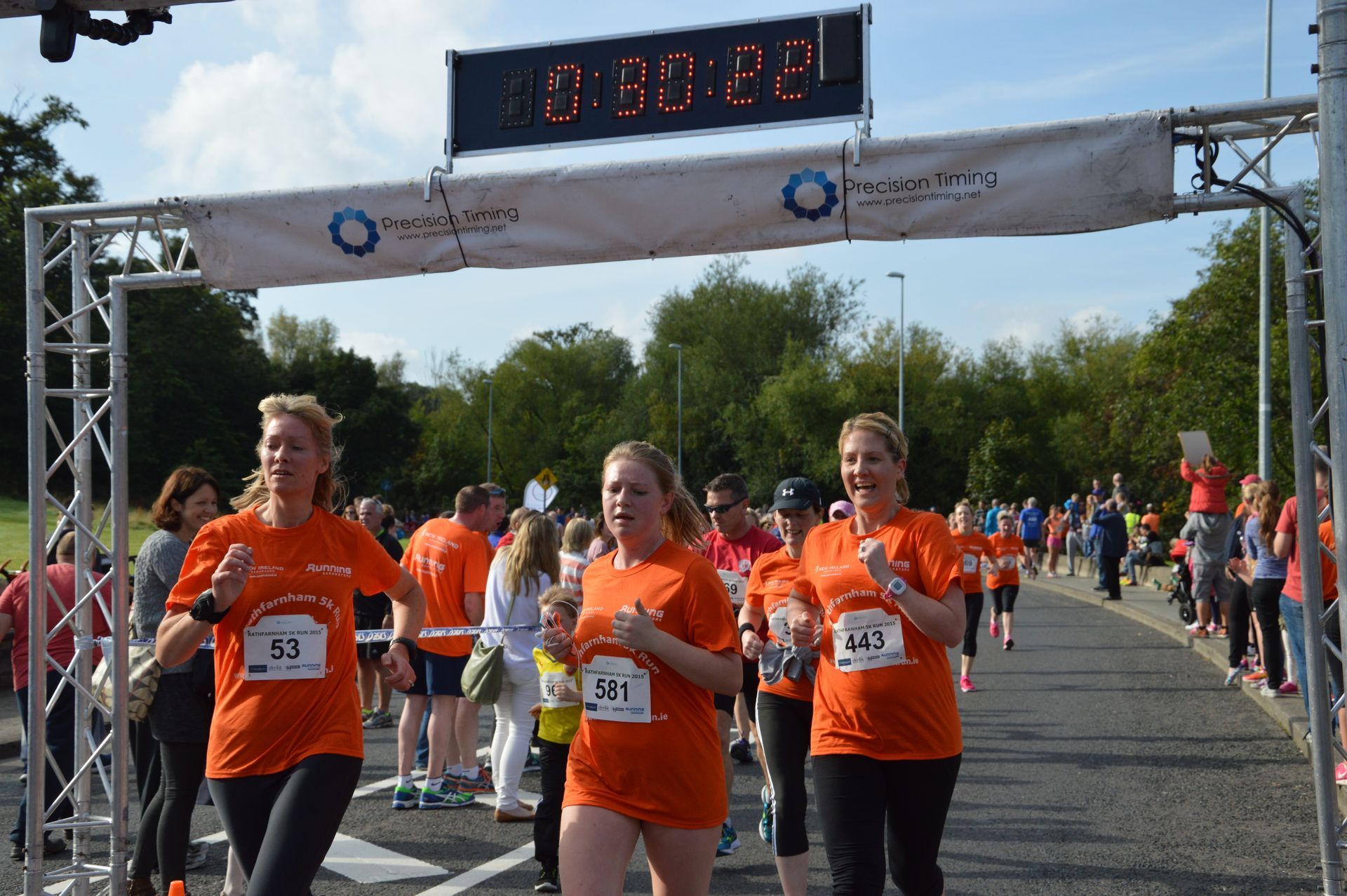 Three women in orange shirts are running in a race.