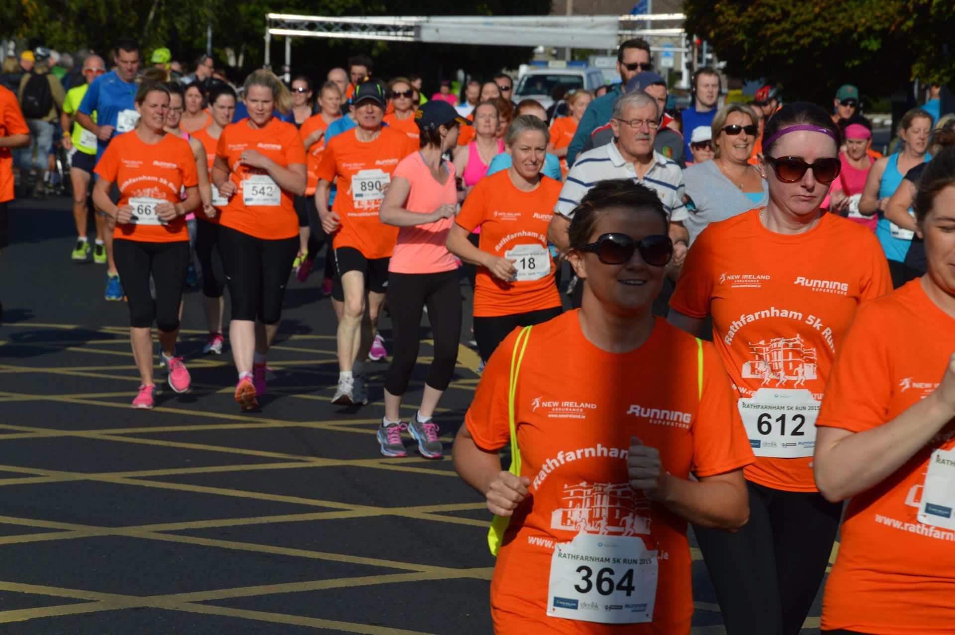A group of people wearing orange shirts are running a race.