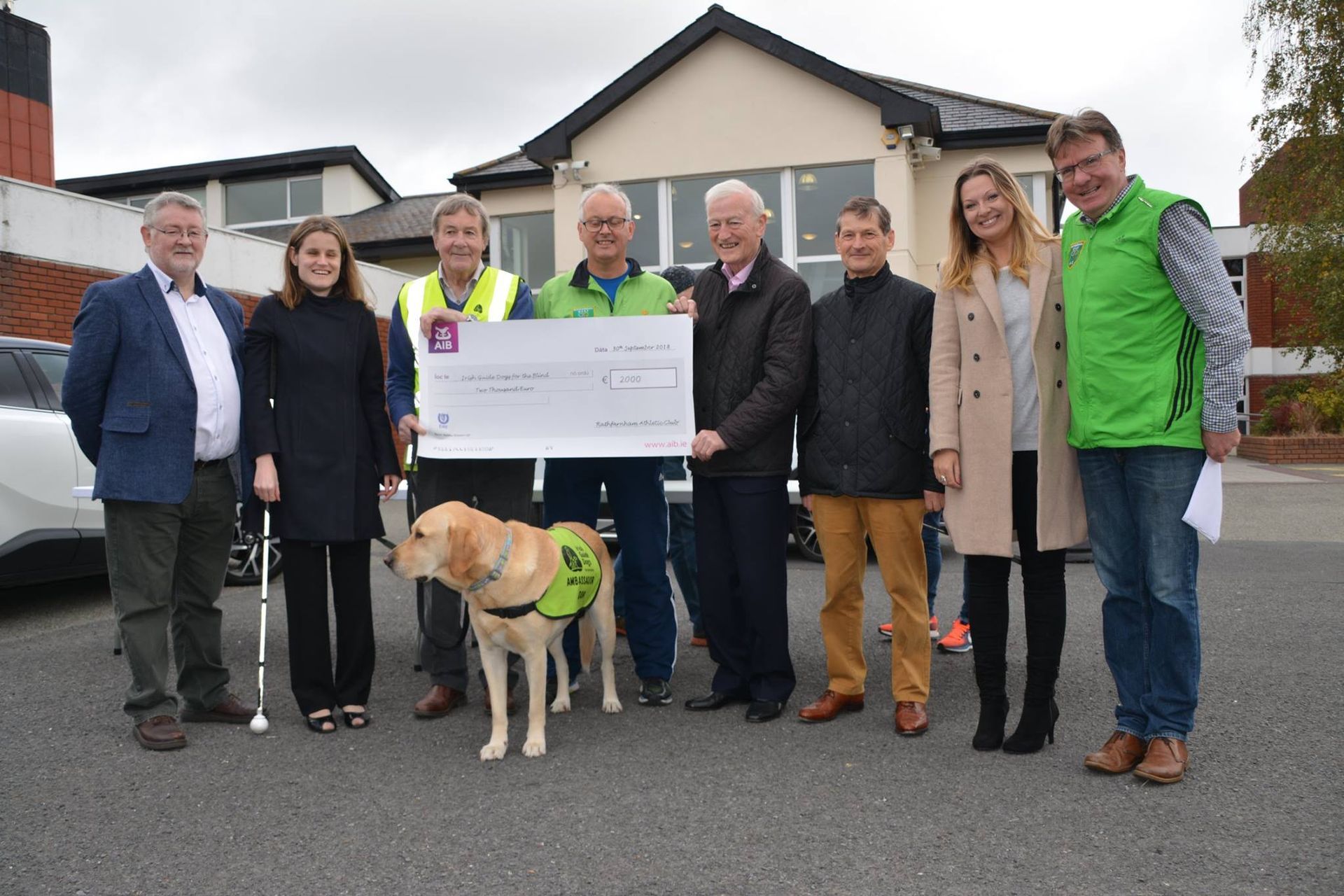 A group of people standing in front of a building holding a large check.