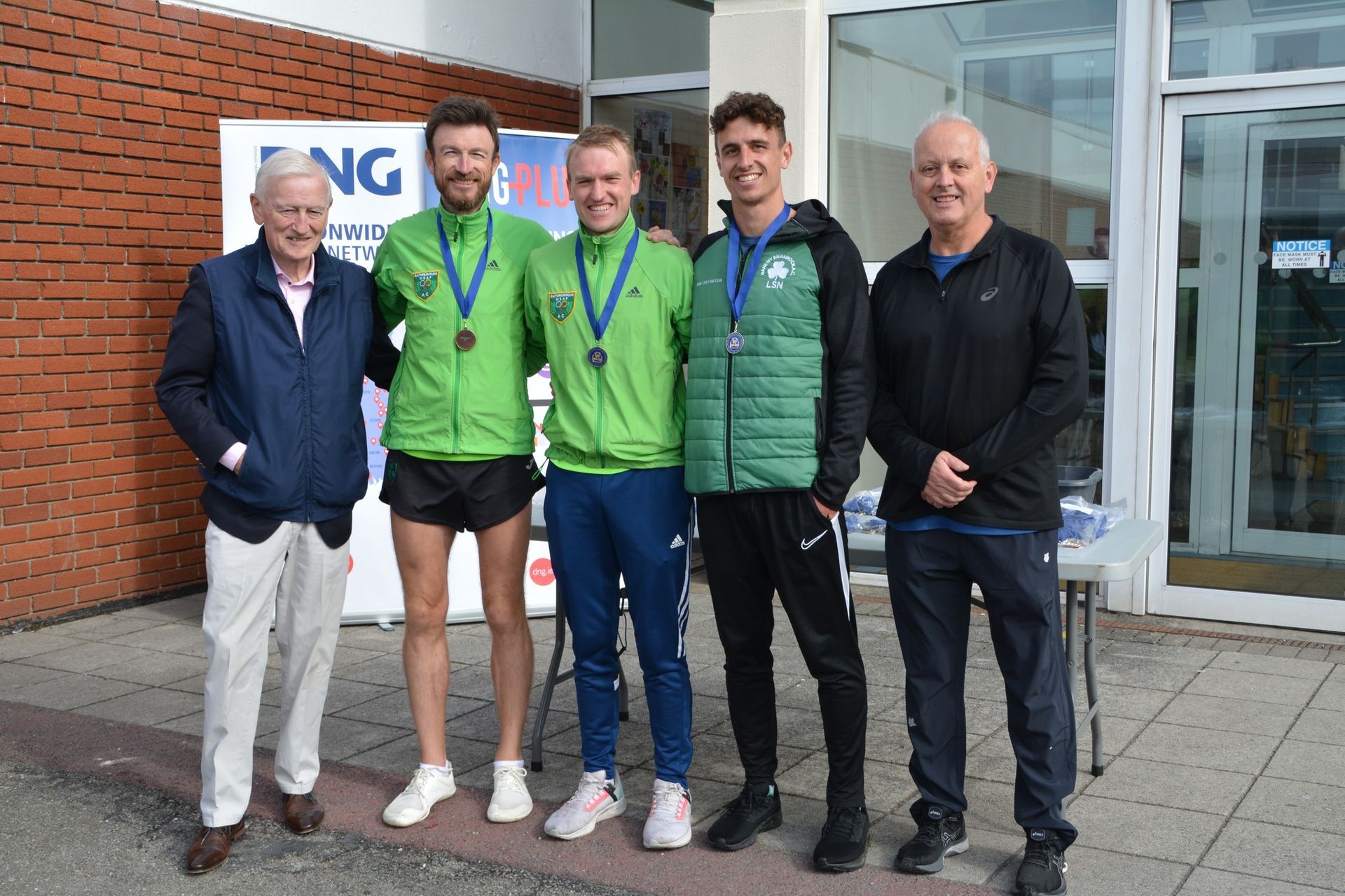 A group of men are posing for a picture in front of a building.