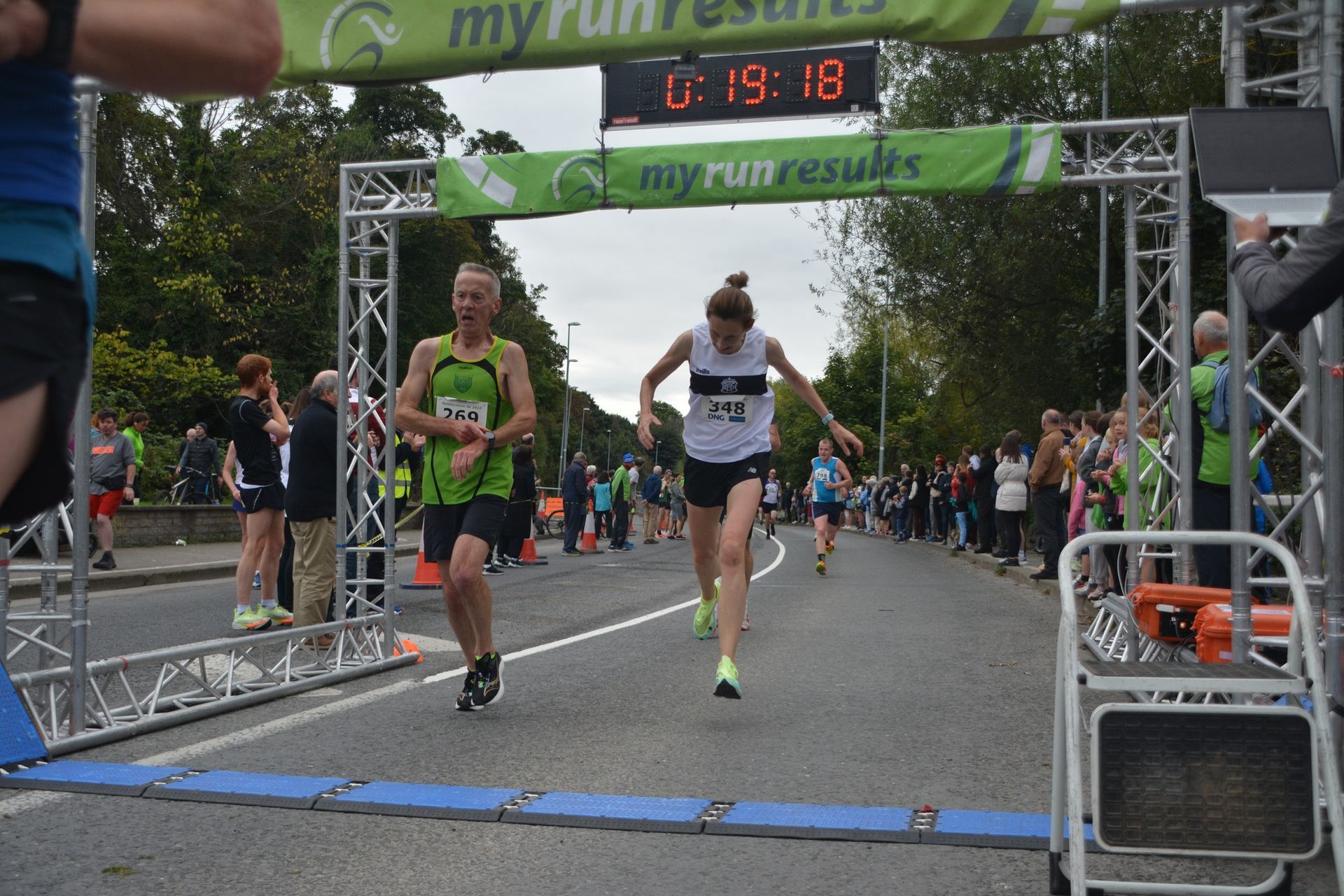 A man and a woman are crossing the finish line of a marathon