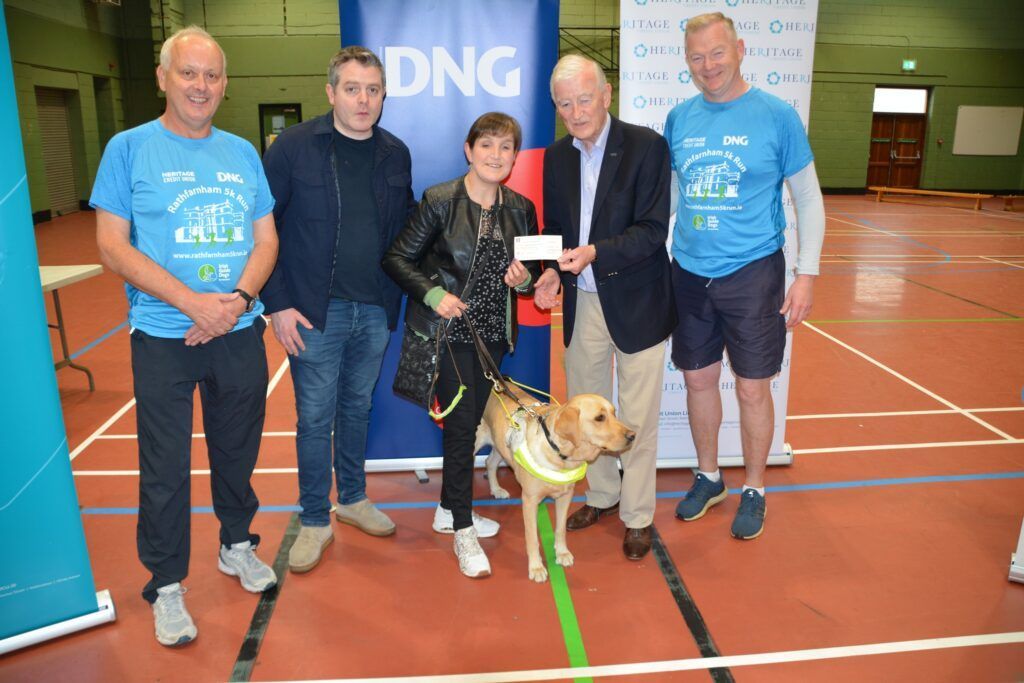 A group of people standing next to a dog in a gym.