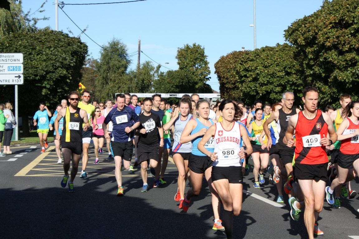 A group of runners are running down a street with a sign that says exit on it