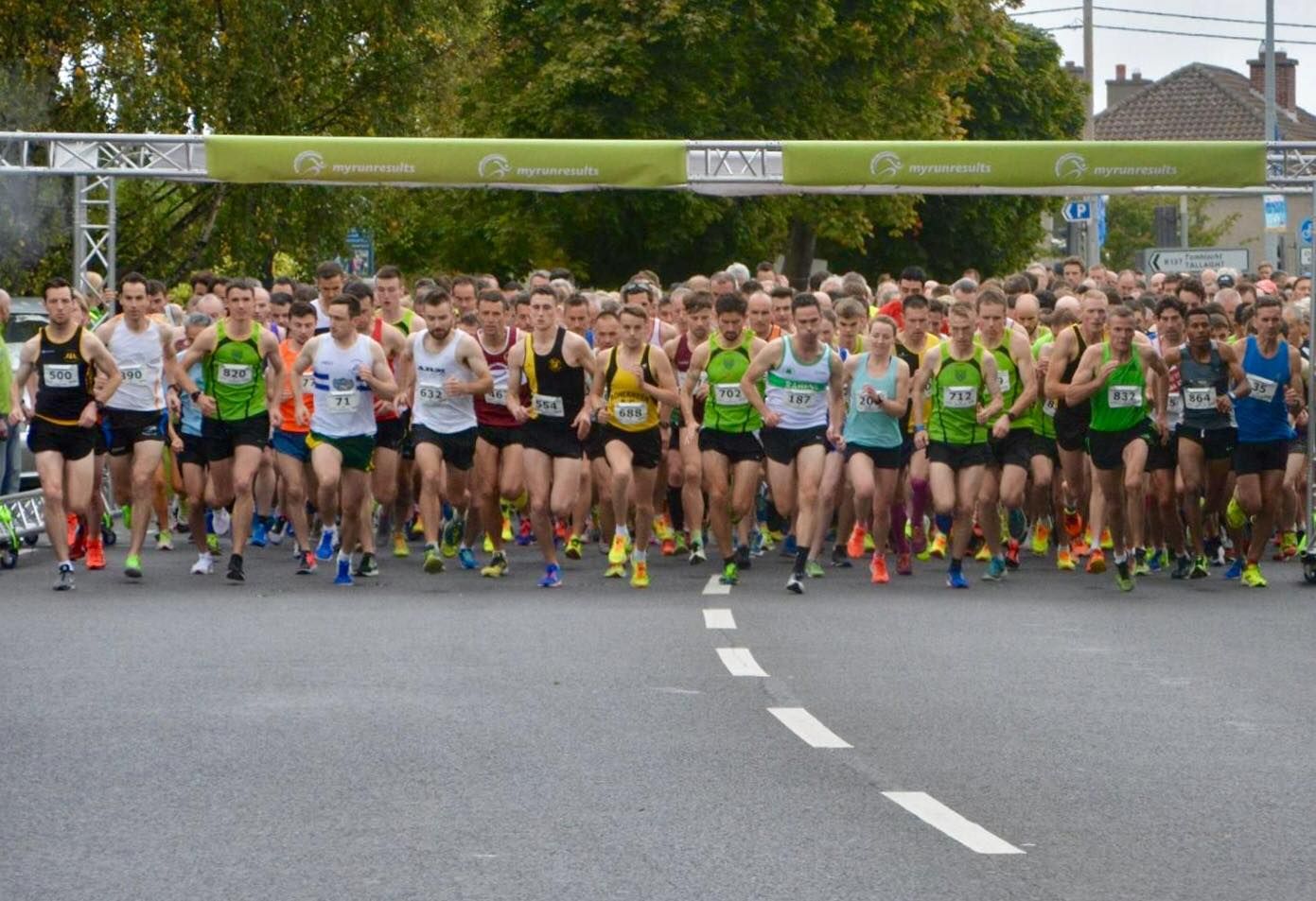 A large group of people are running a marathon on a street.