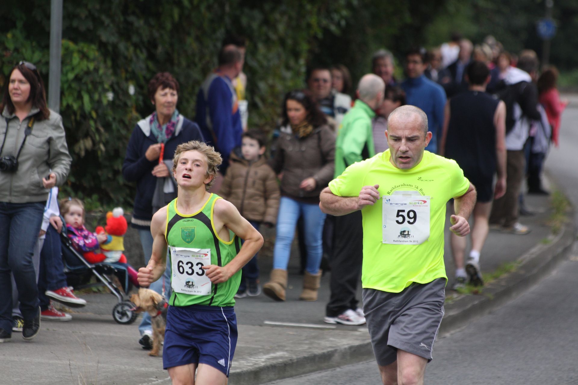 A man in a neon green shirt with the number 59 on it is running a race