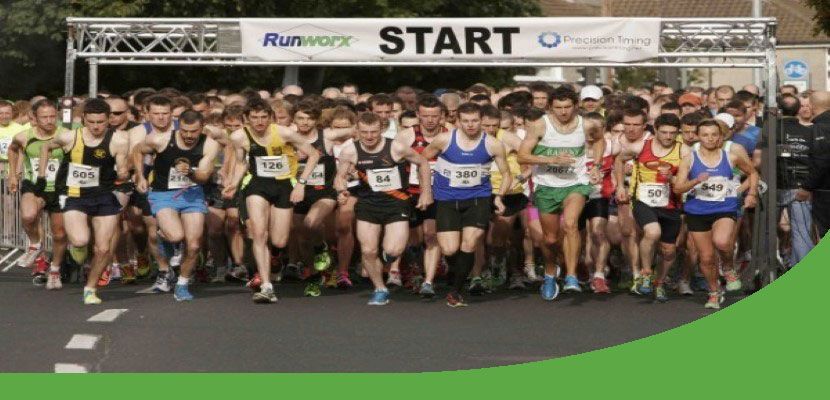 A group of people are running a marathon at the start line.