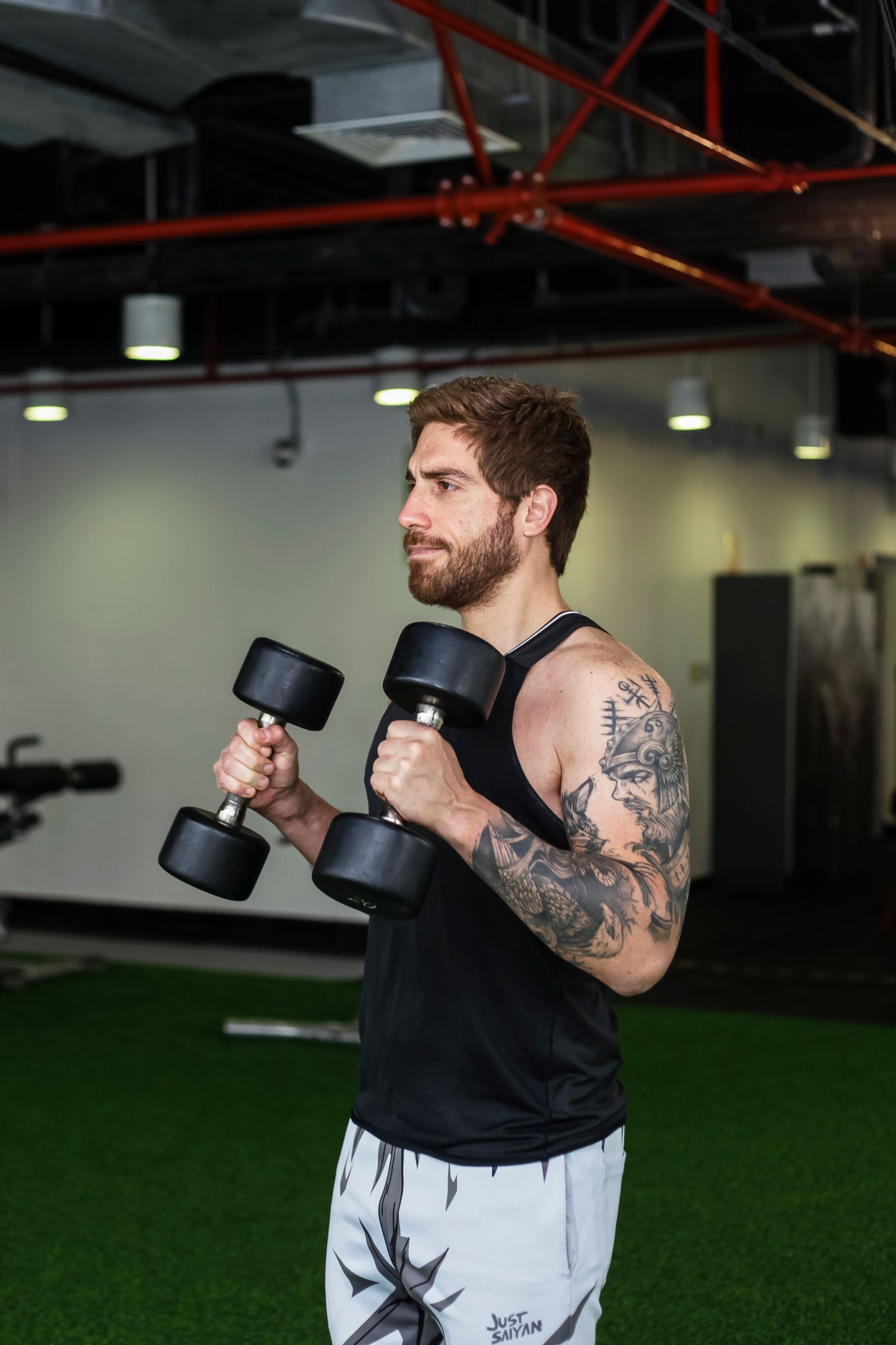 Un hombre sostiene dos mancuernas en sus manos en un gimnasio.