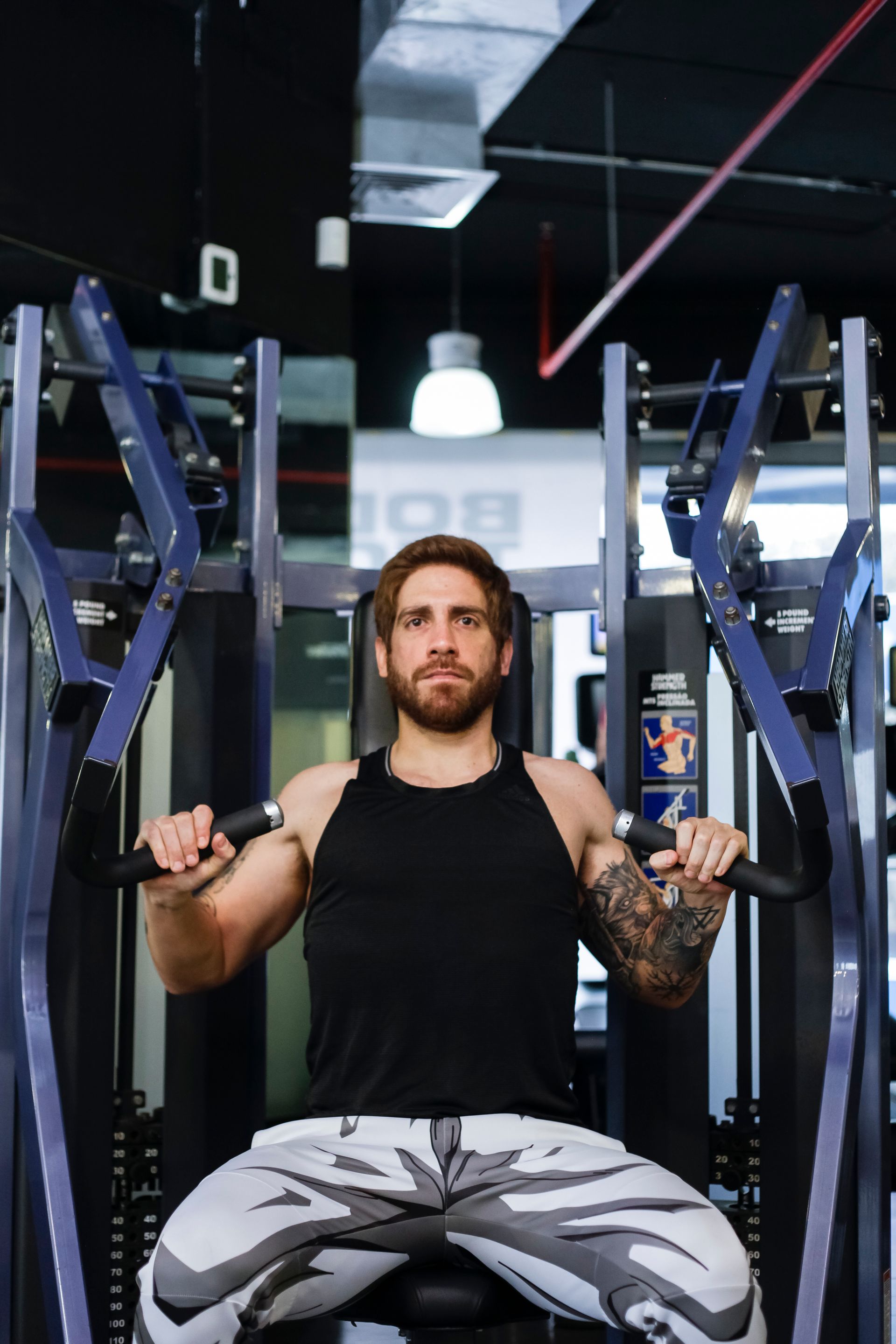 Un hombre está sentado en una máquina en un gimnasio.