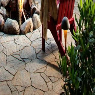 Stone patio with a fire pit, red Adirondack chair, and a garden light.
