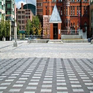 Brick plaza with geometric pattern, leading to buildings of varying architecture.