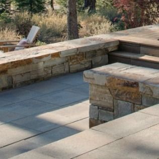 Stone patio with steps and retaining walls, in a natural setting.