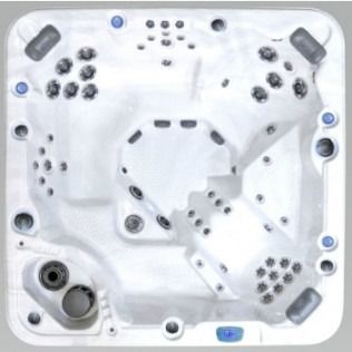 Top-down view of a white, square hot tub with multiple jets, seating areas, and a central elevated section.