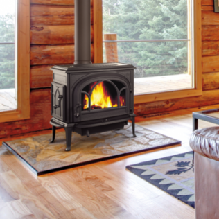 Black wood-burning stove with flames, in a log cabin style room, on a tiled hearth.