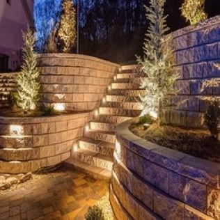 Stone steps and retaining walls with built-in lights, landscaping at night.