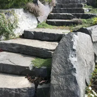 Stone steps leading upwards, flanked by large rock formations in a natural outdoor setting.
