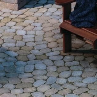 Stone patio with a wooden chair and blue blanket.