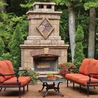 Outdoor stone fireplace with seating area; orange cushions, black metal frames.