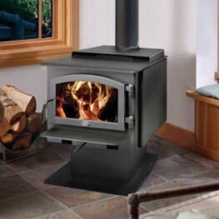 Wood-burning stove with flames visible in the glass door, with a black metal body, set in a room.