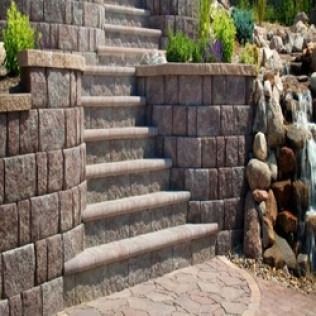 Stone steps and retaining walls in a landscaped garden with a small waterfall.