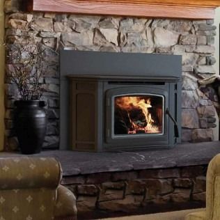 Fireplace insert in a stone hearth with burning logs.