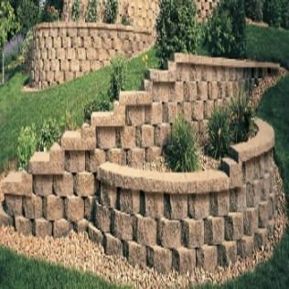 Stone retaining walls on a grassy slope, with steps and planted areas.