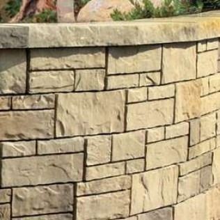 Stone wall with varying sizes of light brown rectangular blocks.