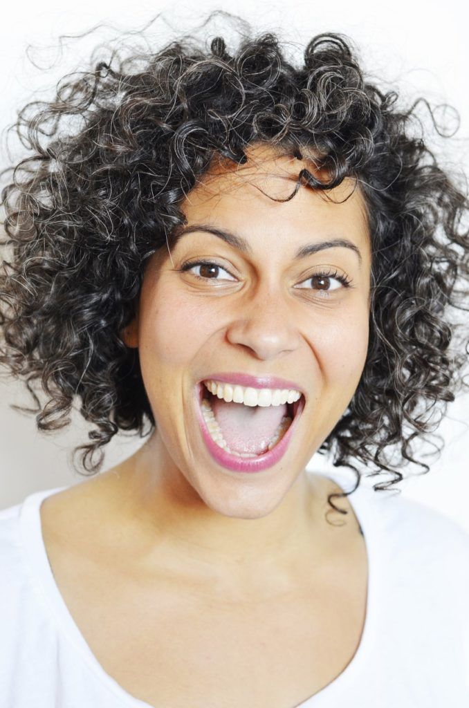 Headshot of Liza Paul. She is smiling joyfully and wearing a white t-shirt against a white backdrop.