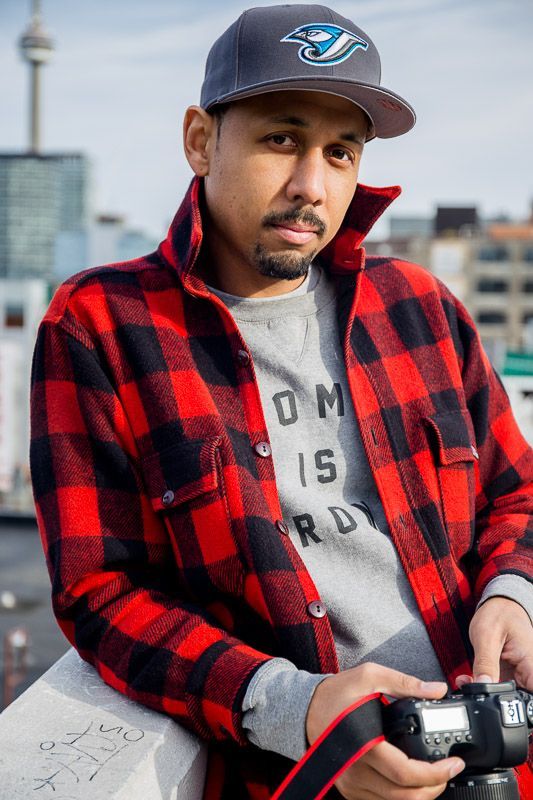 A man wearing a plaid shirt and a hat is holding a camera.