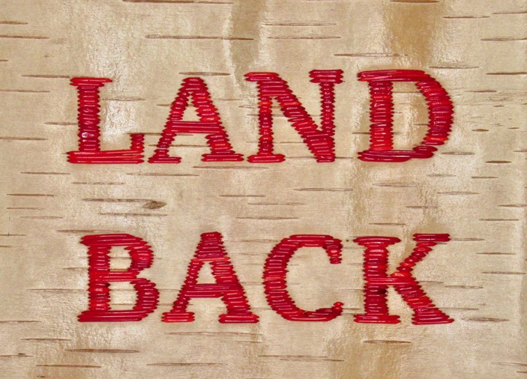 A patch that says Land Back in red letters