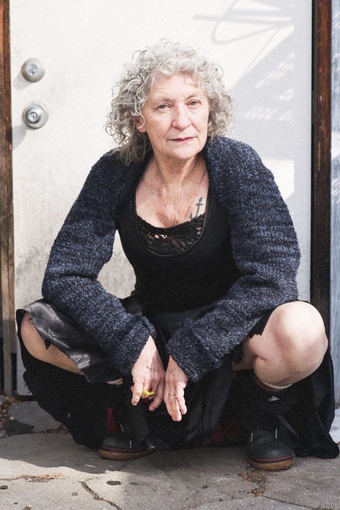 A woman is squatting down in front of a white door