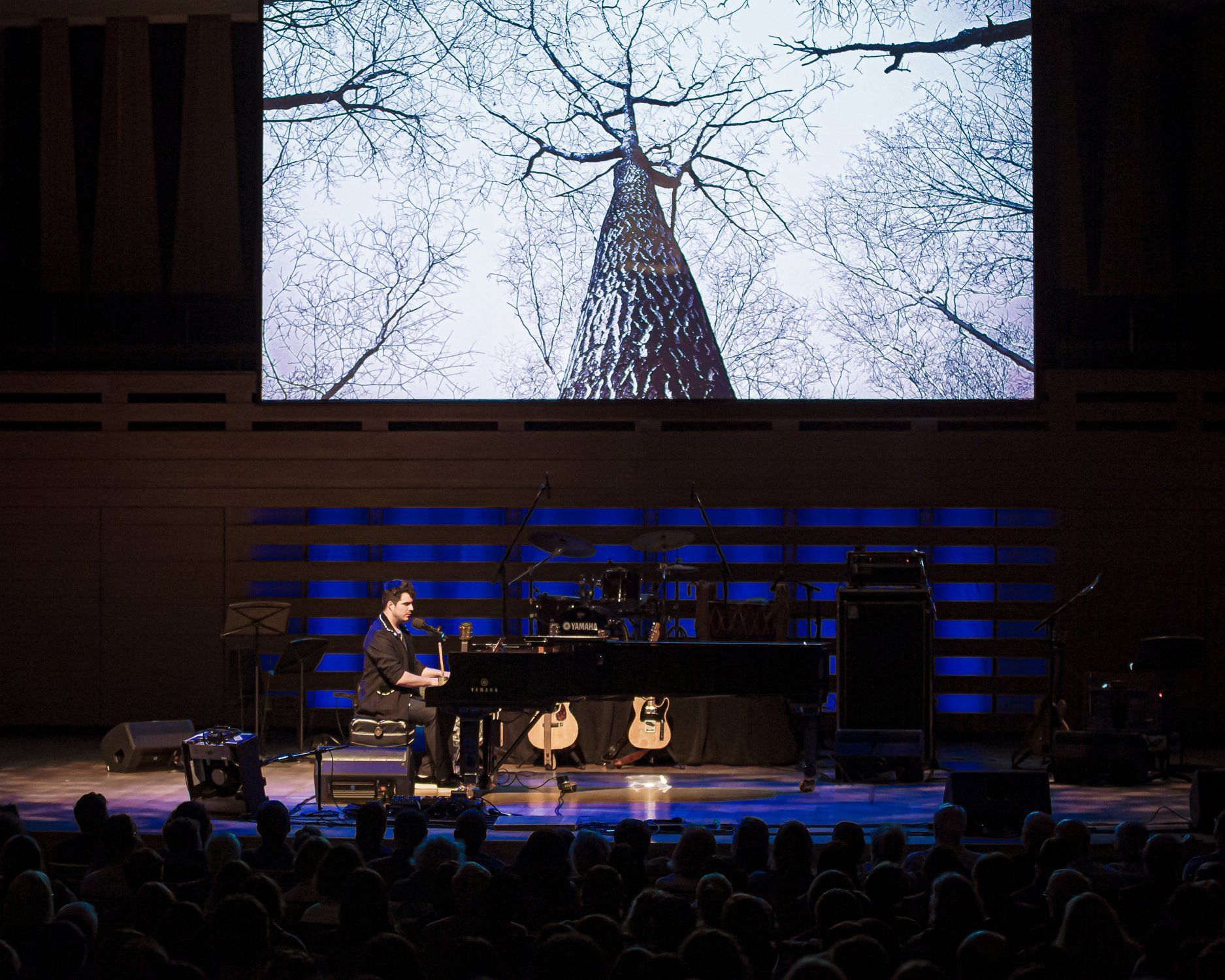 A man playing a piano in front of a large screen