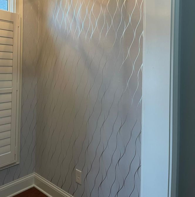 A room with a white wall and a window with shutters.