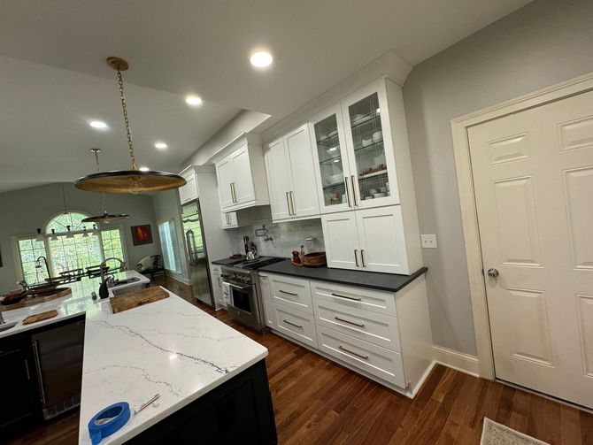 A kitchen with white cabinets , black counter tops , and stainless steel appliances.