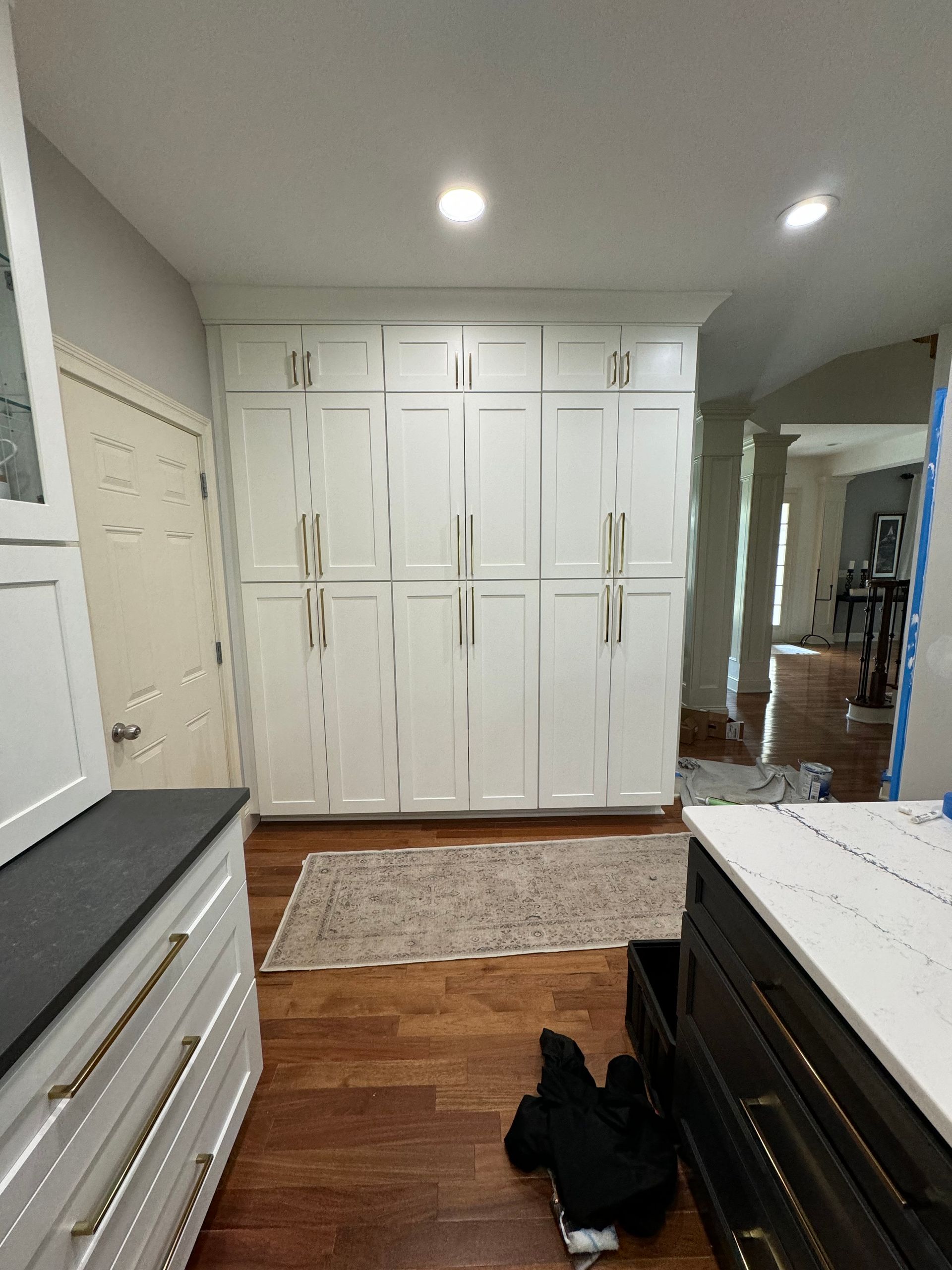 A kitchen with white cabinets and wooden floors