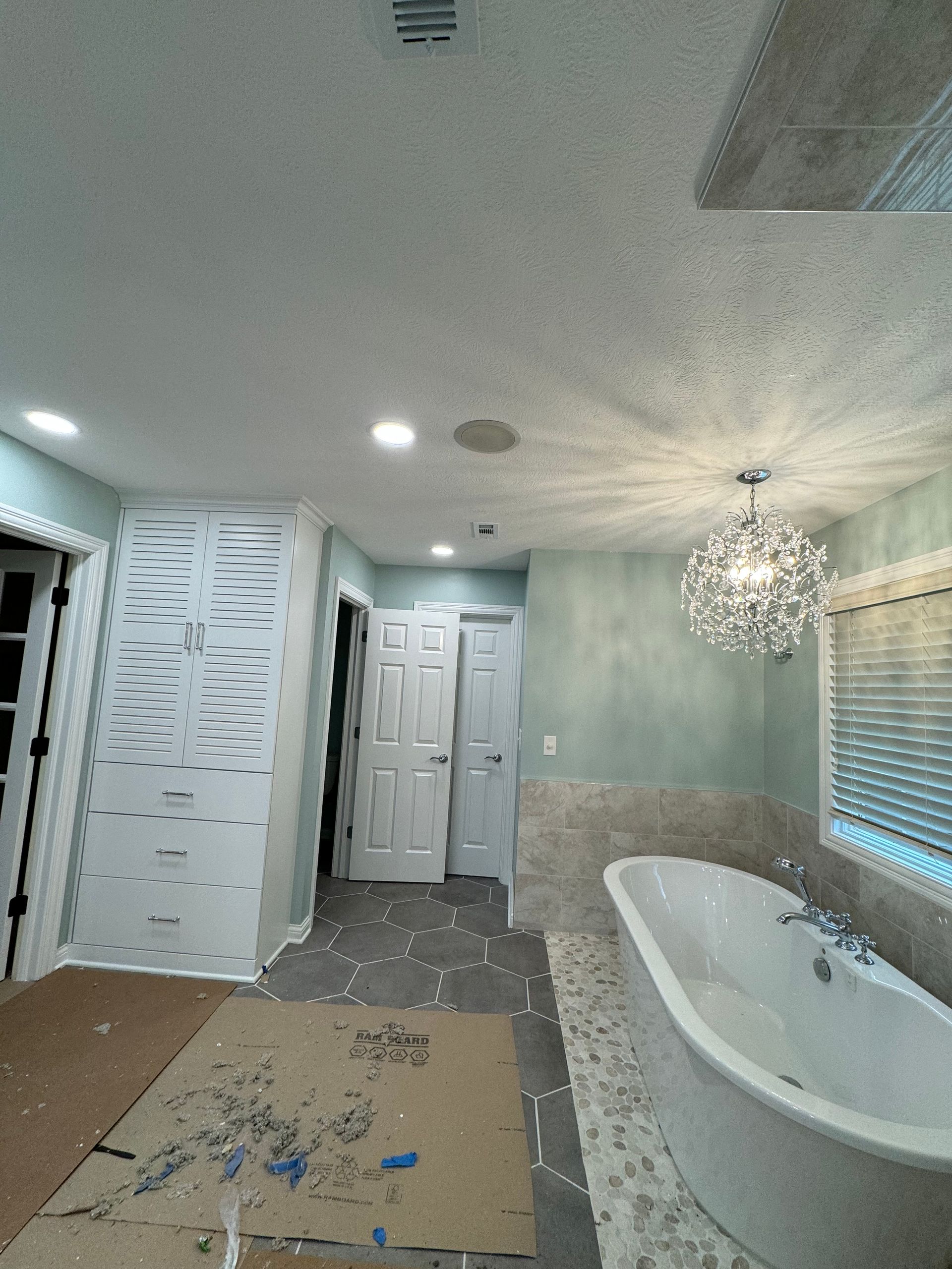 A bathroom with a tub and a chandelier hanging from the ceiling.