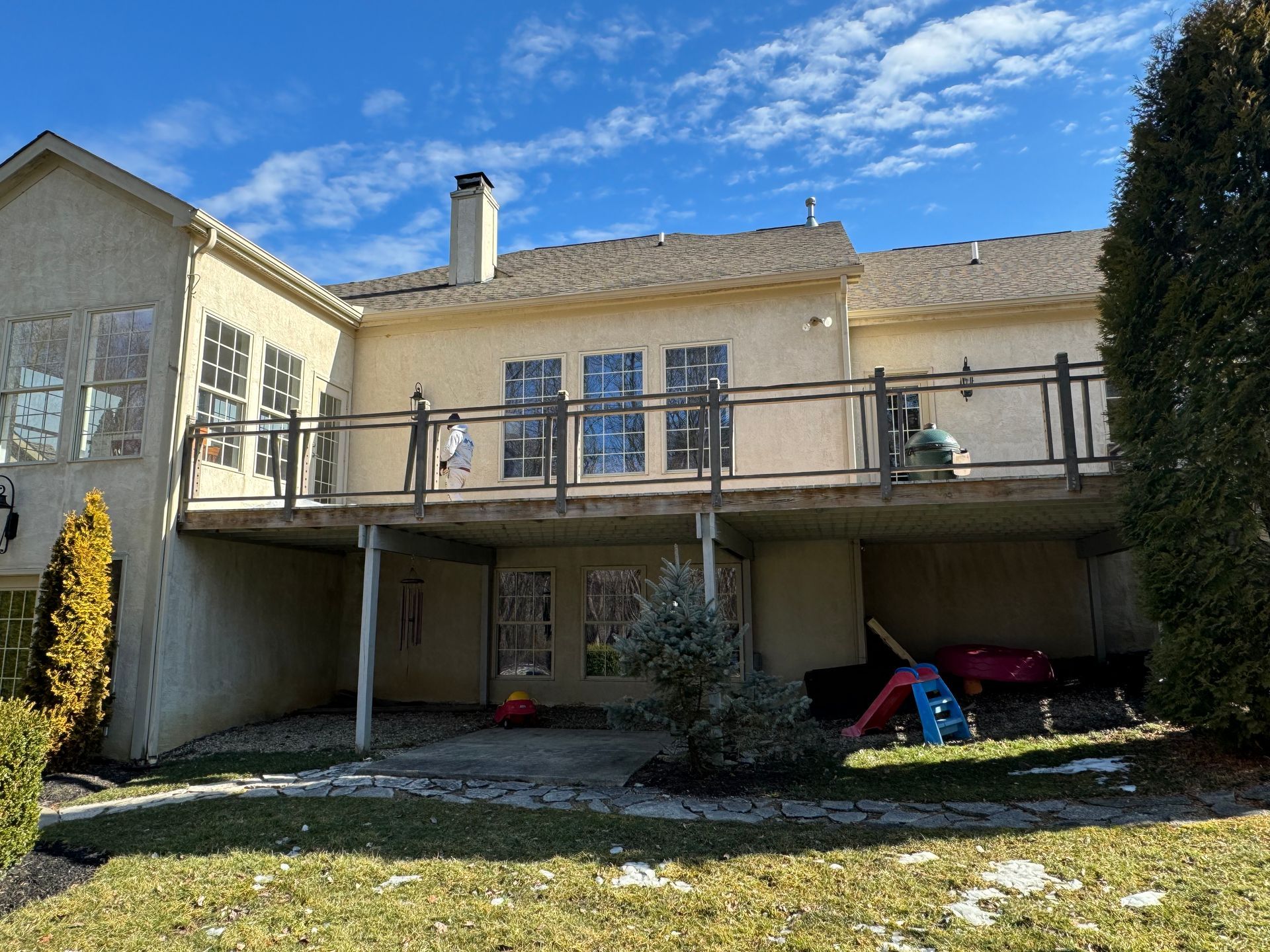 A large house with a large deck and a playground in the backyard.
