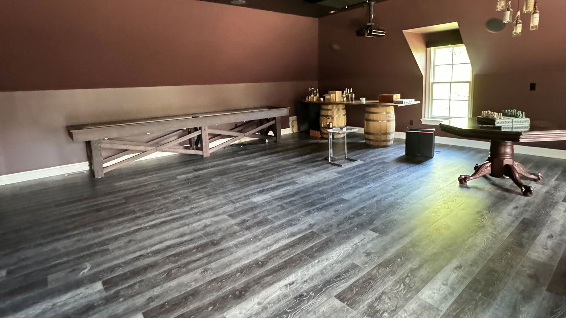 A room with wooden floors , a table , benches and barrels.