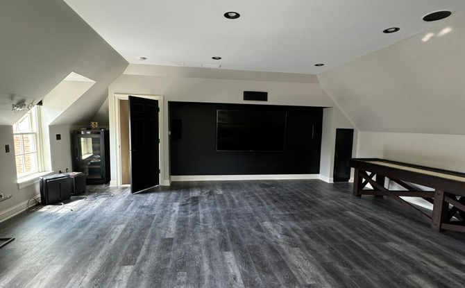 A large empty room with a wooden table and a black wall.