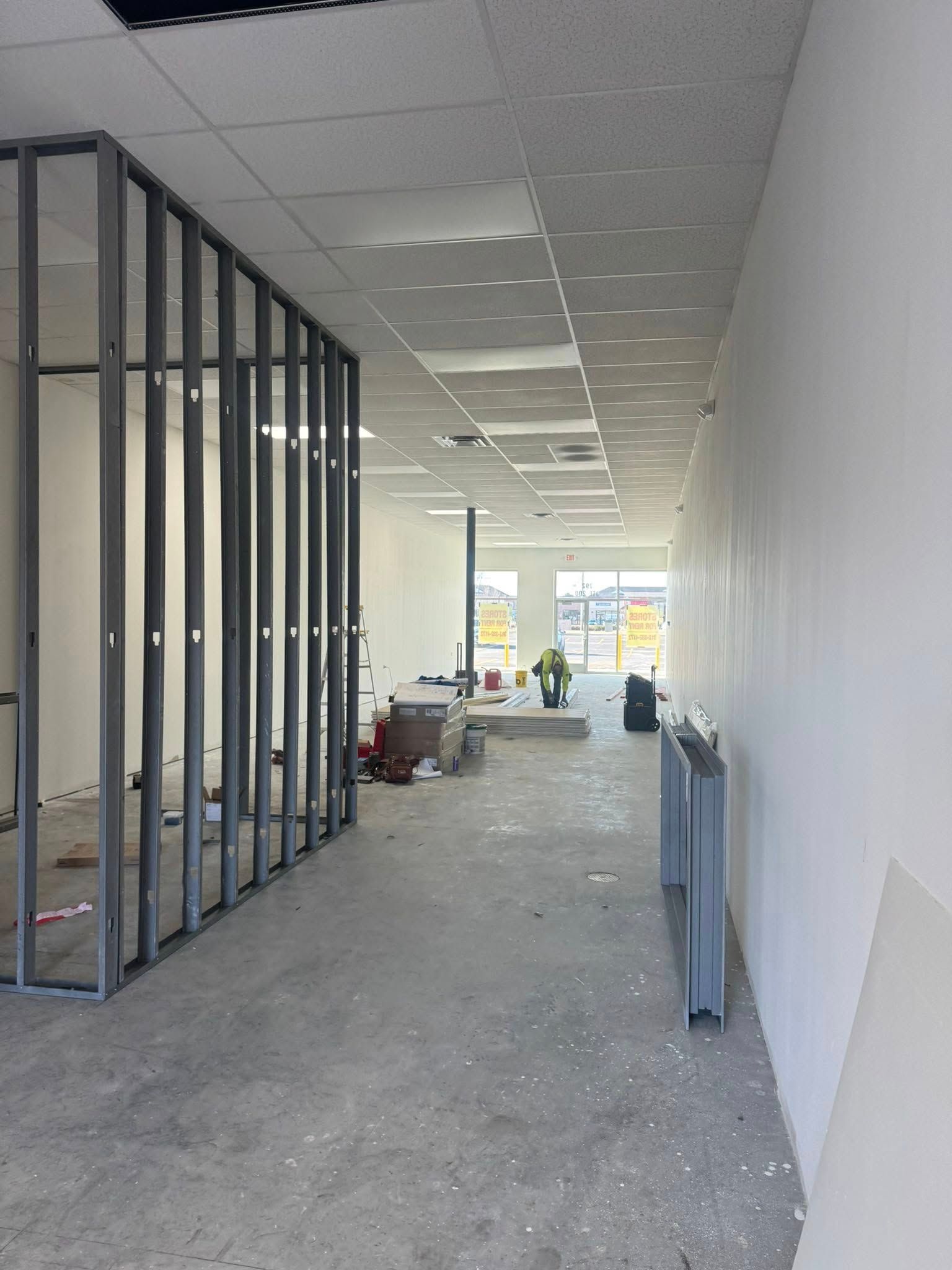 Interior construction site with metal stud framing, unfinished walls, and concrete floor.