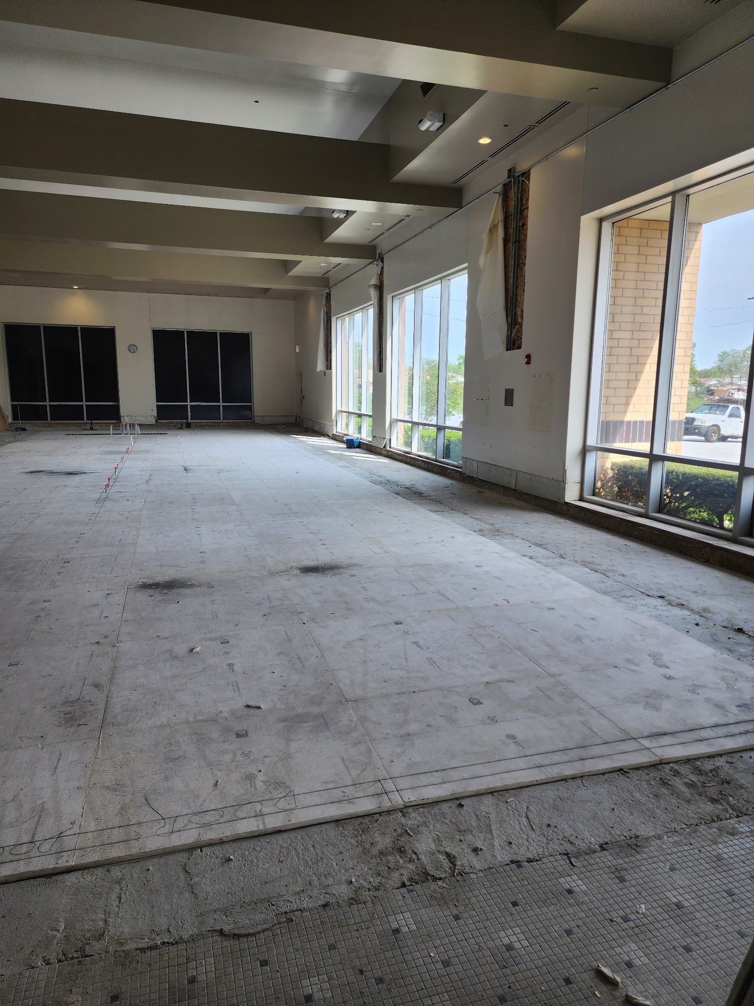 Empty interior space with concrete floor, large windows, and exposed walls.
