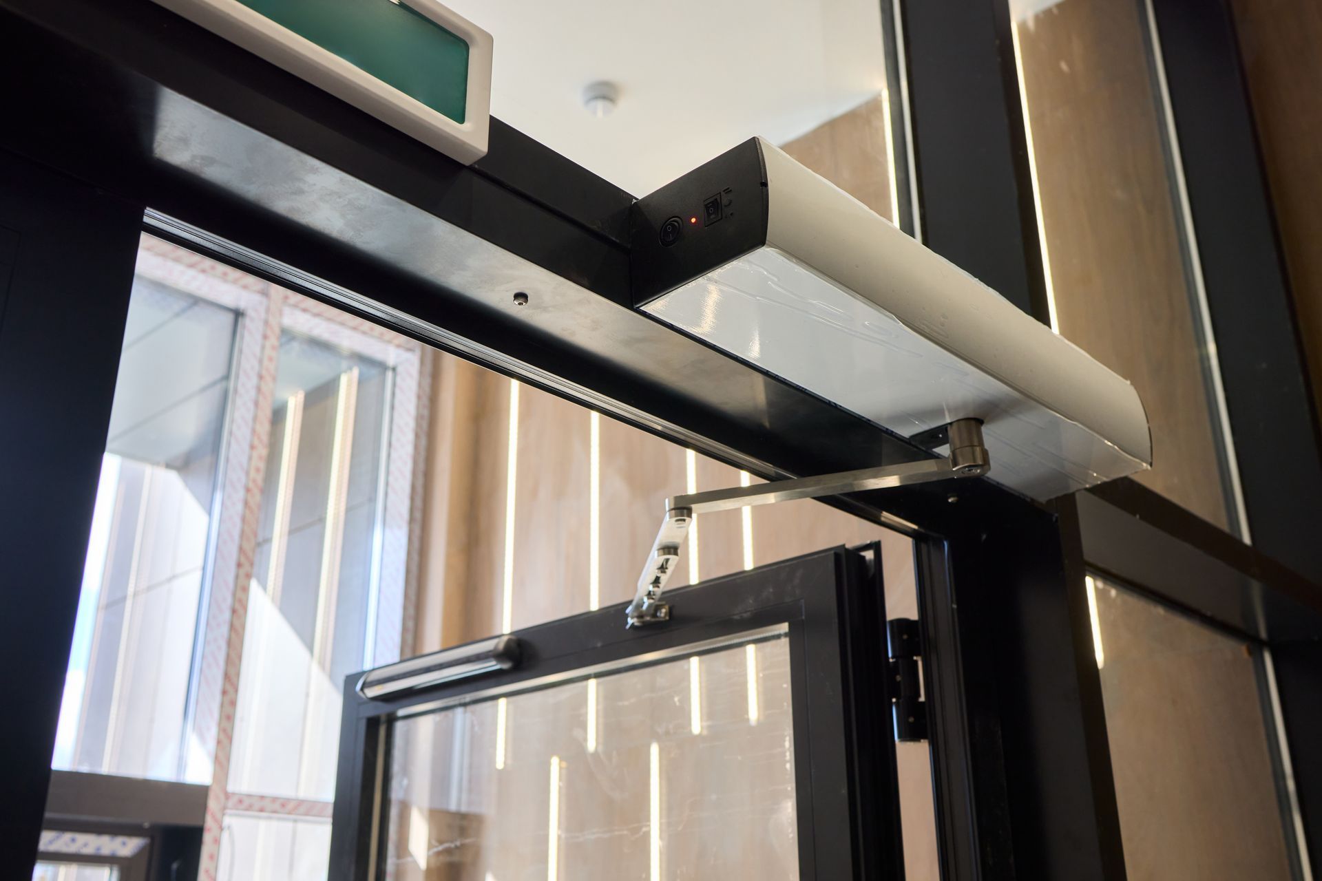 Door with an automatic closer, glass panel, and exit sign above.