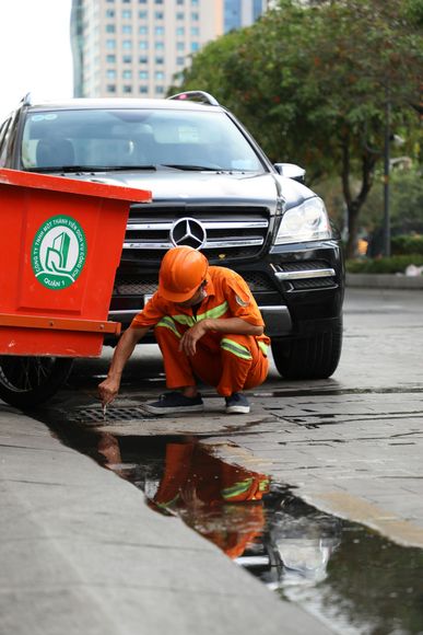 A man is cleaning a puddle next to a mercedes car.